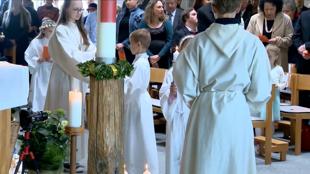 Kind zündet eine Kerze während einer kirchlichen Feierlichkeit an
